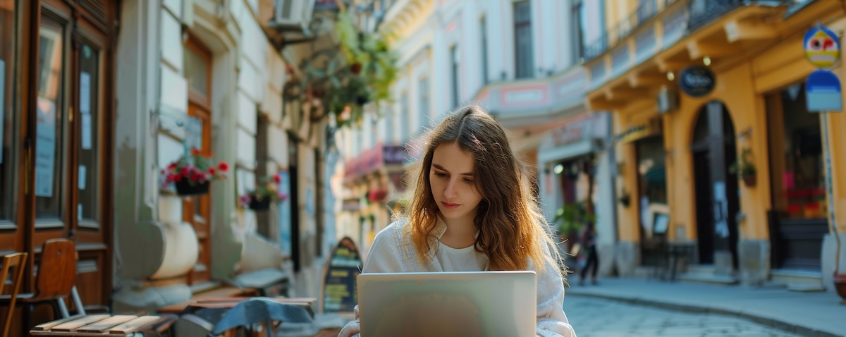 Young woman learning Romanian on a laptop with a Bucharest street in the background