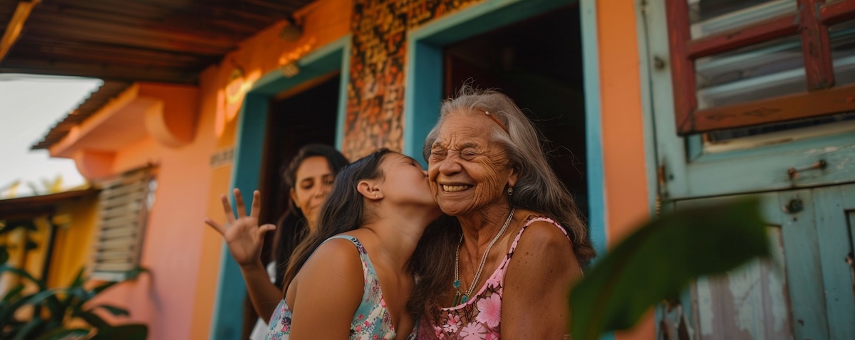 Brasiliansk bestemor hilser på en norsk kvinne med et kyss på kinnet ved inngangsdøren