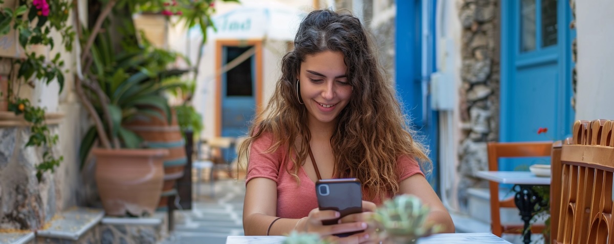Learner practising Greek with a language app on a smartphone in a Greek cafe