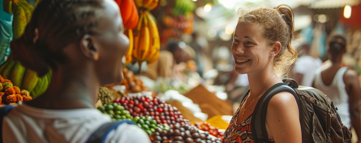 Traveller learning Swahili chats with a market vendor at a spice stall in Stone Town, Zanzibar